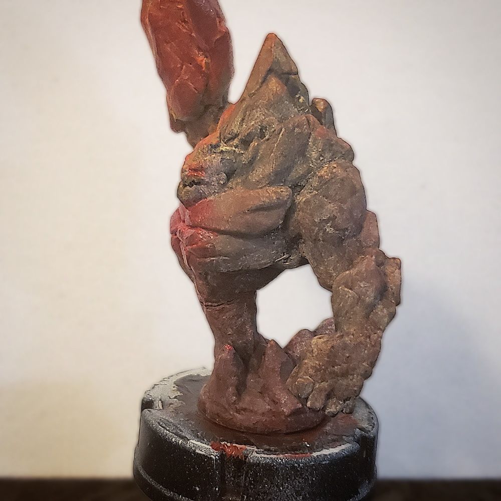An Earth elemental mini, with his right arm raised up like a club. Painted with florescent colors so that the upraised arm glows like lava. (View of side without the club arm, showing the texture of the paints.)
