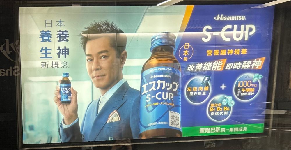 香港のエスカップの広告。ルイス・クーがエスカップの瓶を持ちこちらを見ている。