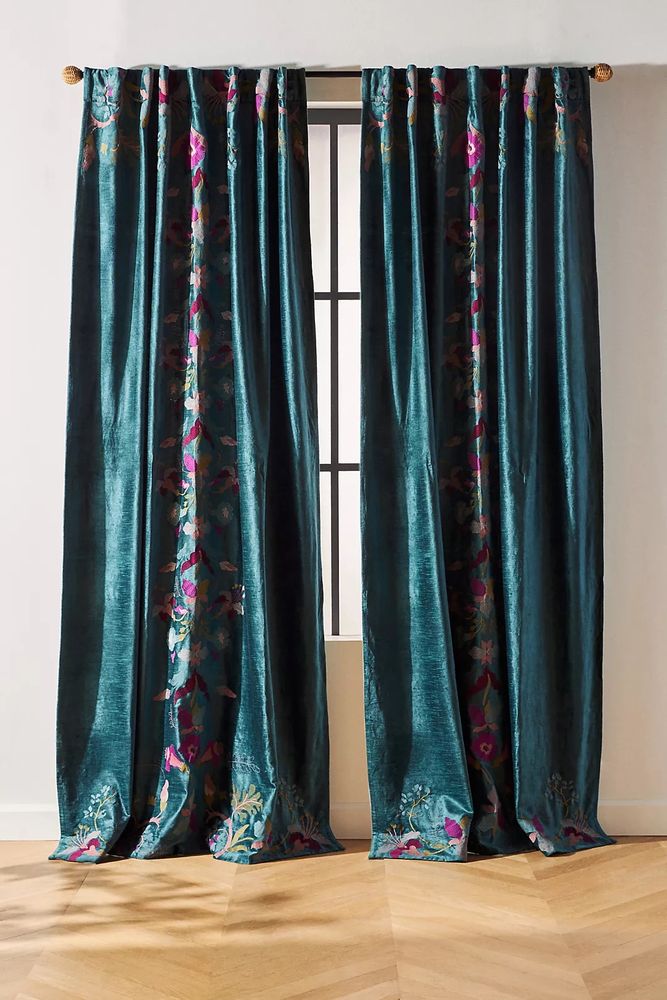 Teal velvet drapes with purple and pink floral embroidery up the center of the panels