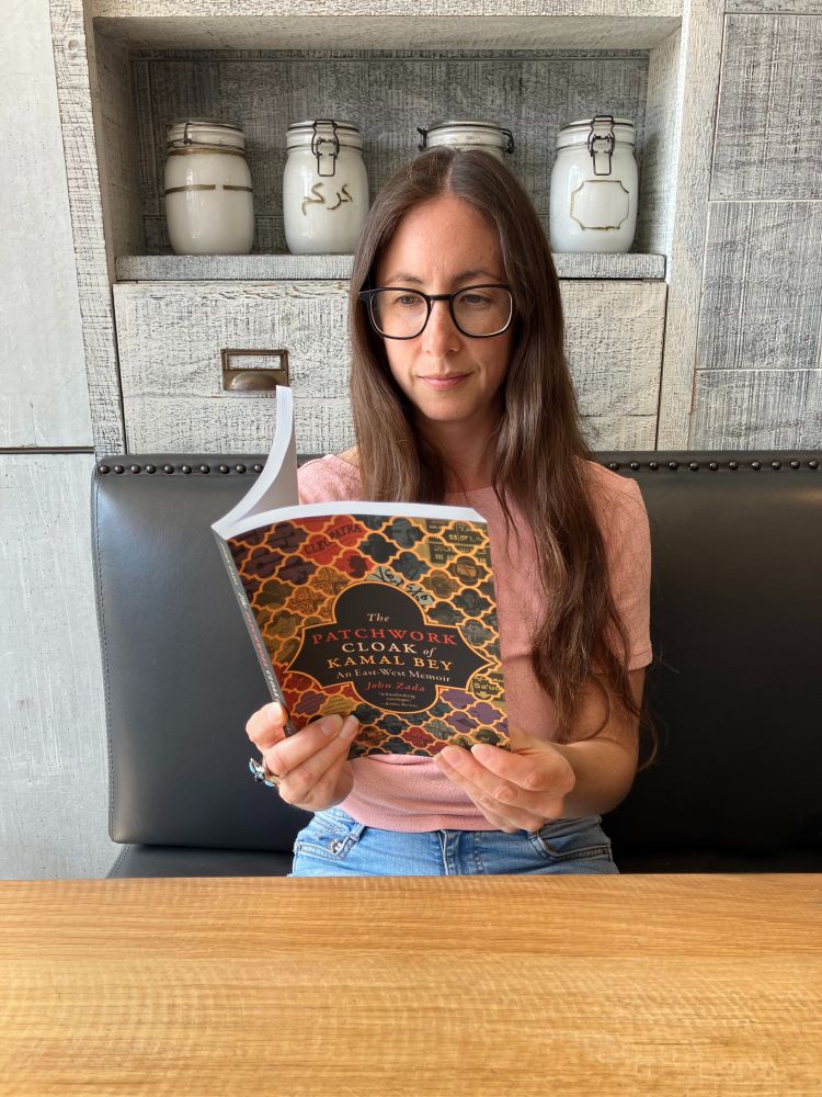 Lori Henry reading the book, The Patchwork Cloak of Kamal Bey by John Zada.
