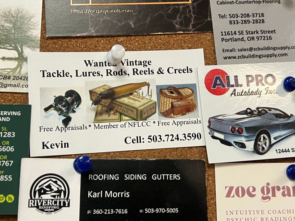 a cork board of business cards and one says “Wanted vintage tackle, lures, rods, reels and creels” Kevin and his phone number very homemade with lil pictures of old fishing stuff 
