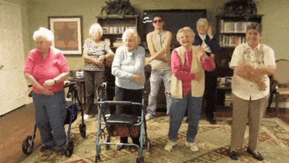 a group of elderly people are standing in a room dancing