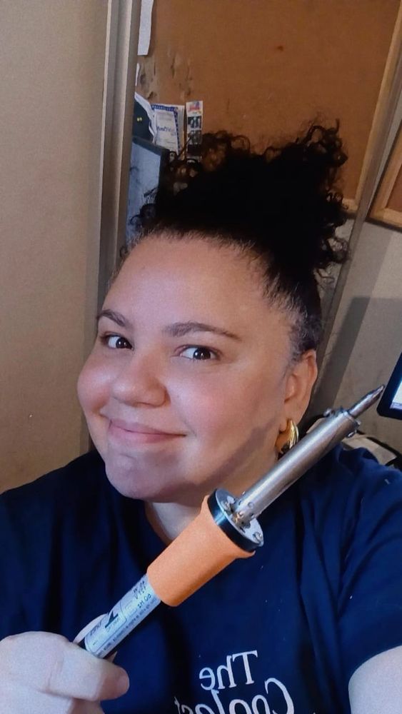 uma foto minha - muher branca, camiseta azul marinho, cabelos cacheados presos num rabo alto segurando um ferro de solda igual ao que o burro do bolsonaro deve ter usado pra tentar abrir a tornozeleira eletrônica
bicho burro da porra