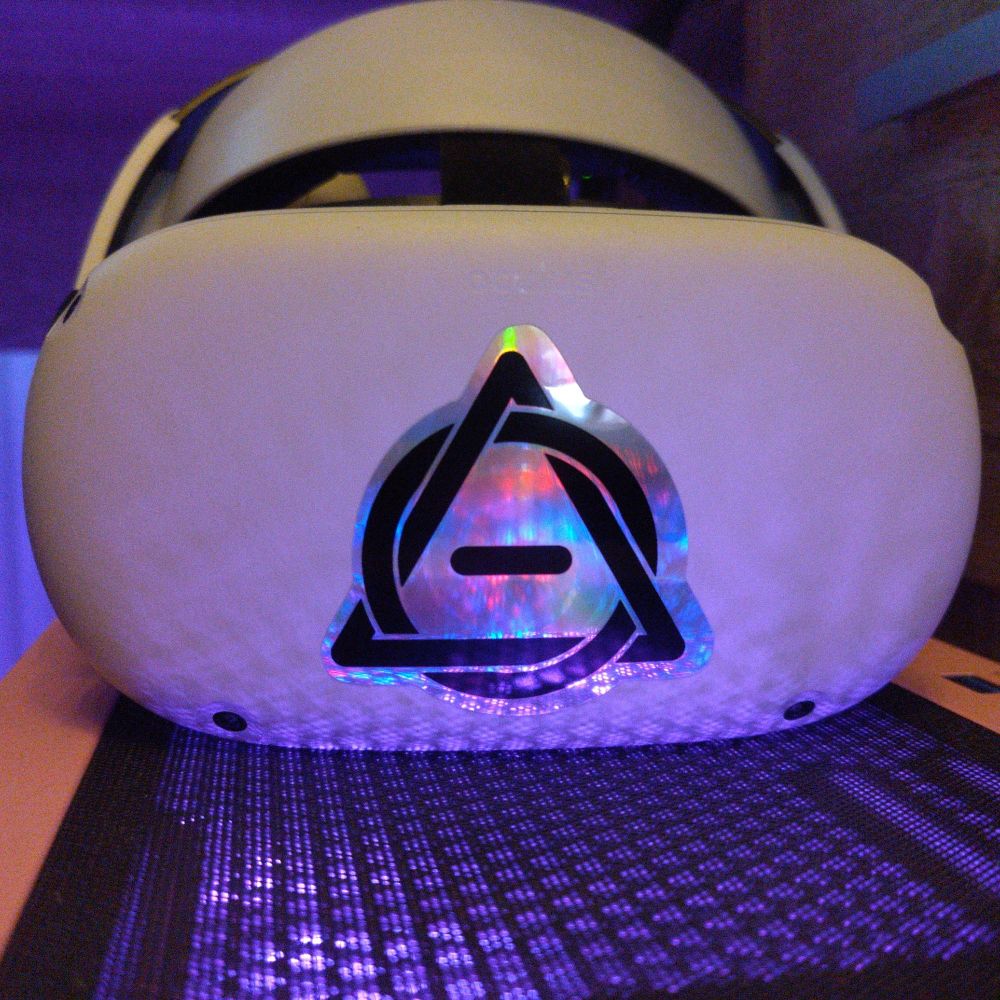 a vr headset with a shiny holographic sticker of a therian symbol, reflecting lots of purple light from the pc its resting on. theres a subtle spiral to the middle of it.