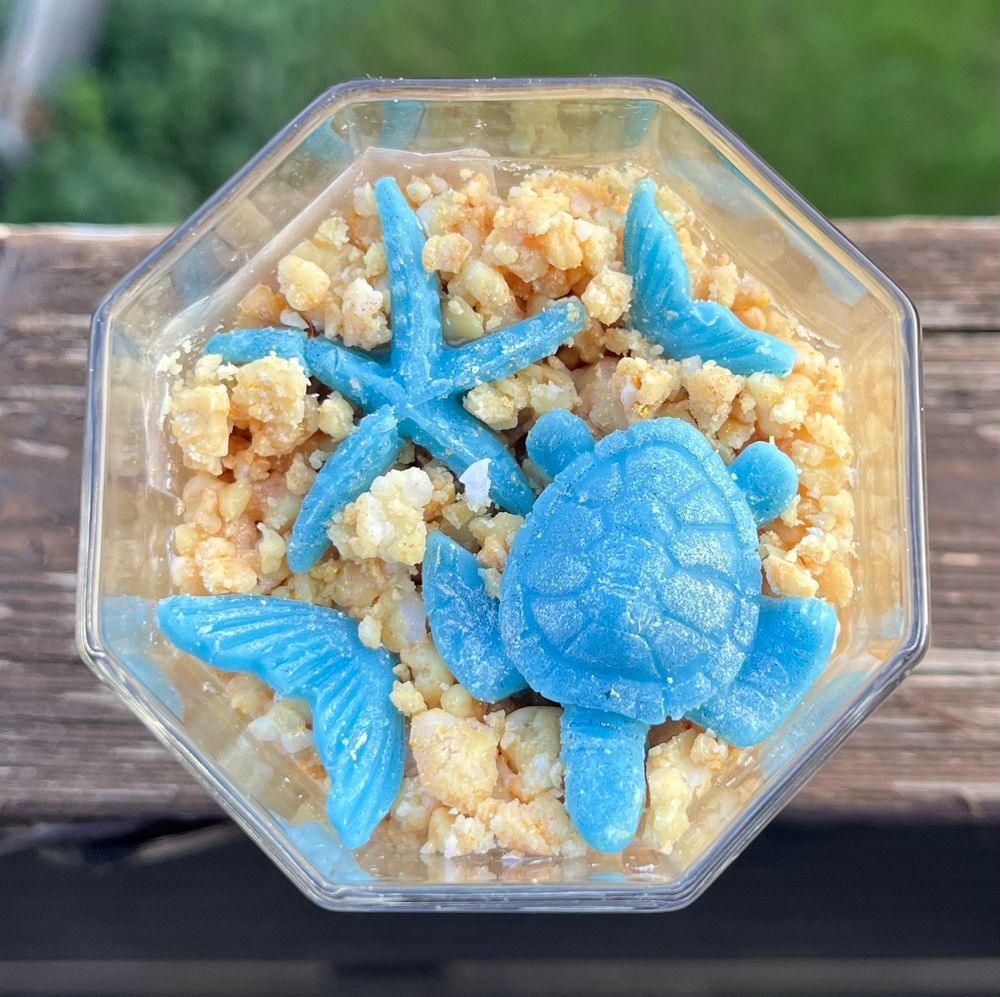 a candle with light brown wax crumbles and a tortoise, a star and two mermaid fins in blue 