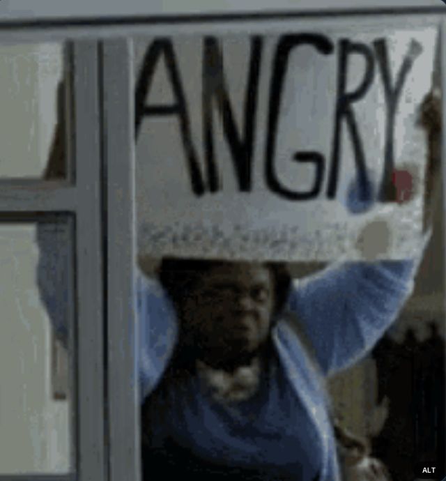 a woman in a window holding up a bedazzled sign that says ANGRY