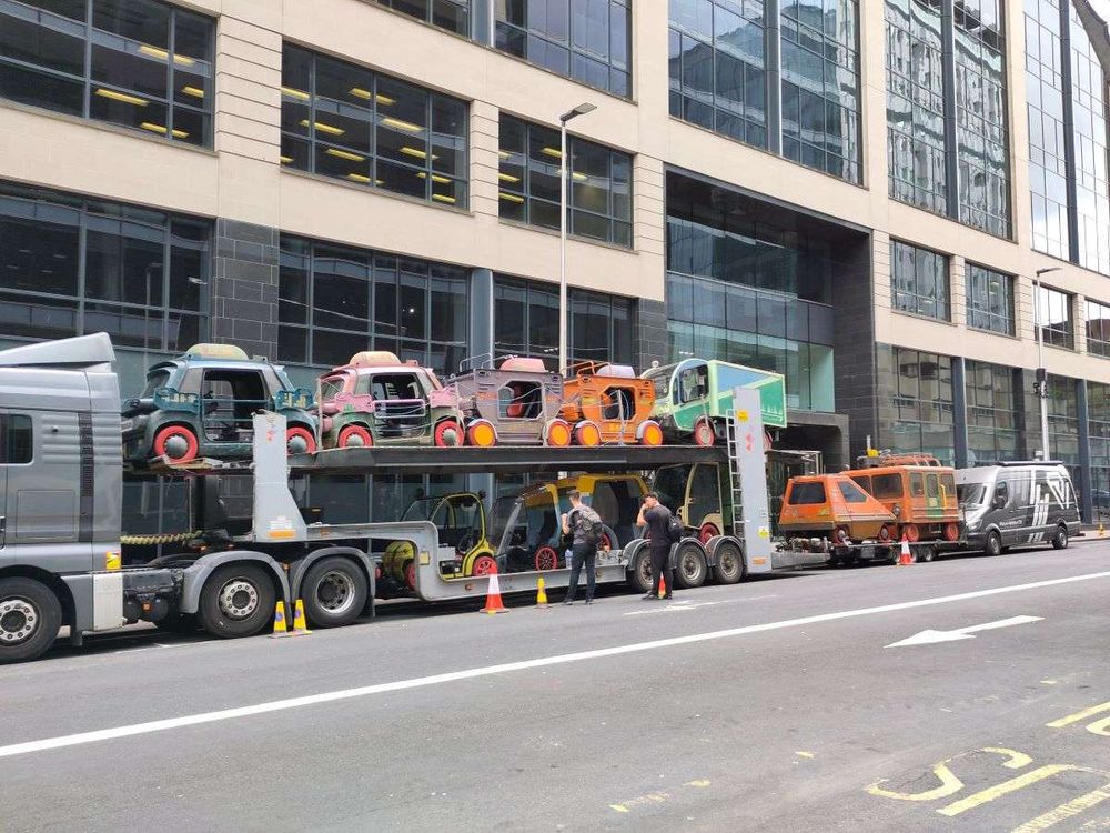 A cartransporter loaded up with small cars that have been modfied for a film, posssibly sci-fi?
