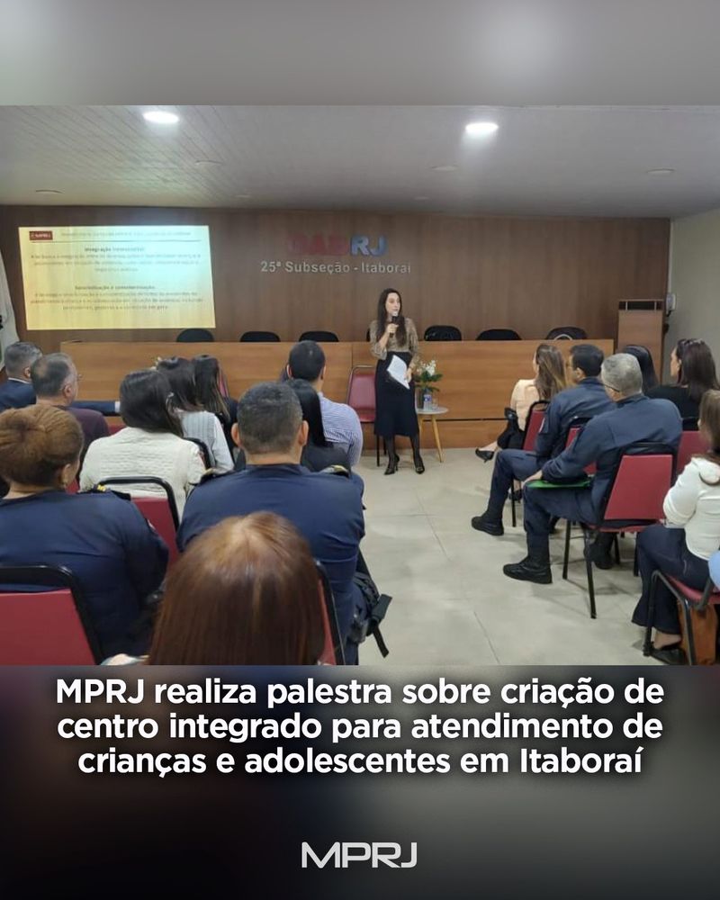 Fotografia de uma palestra realizada pelo MPRJ na sede da OAB em Itaboraí. Uma mulher está em pé, falando ao microfone diante de uma plateia sentada. No fundo, há um telão com apresentação. Na parte inferior da imagem, há o texto: 'MPRJ realiza palestra sobre criação de centro integrado para atendimento de crianças e adolescentes em Itaboraí'.