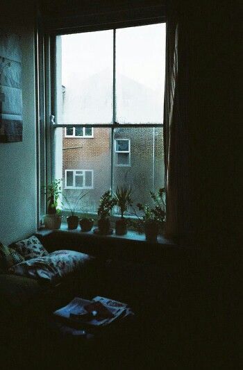 This image captures a rainy night scene viewed from a window, emphasizing a cozy and contemplative rainy night aesthetic