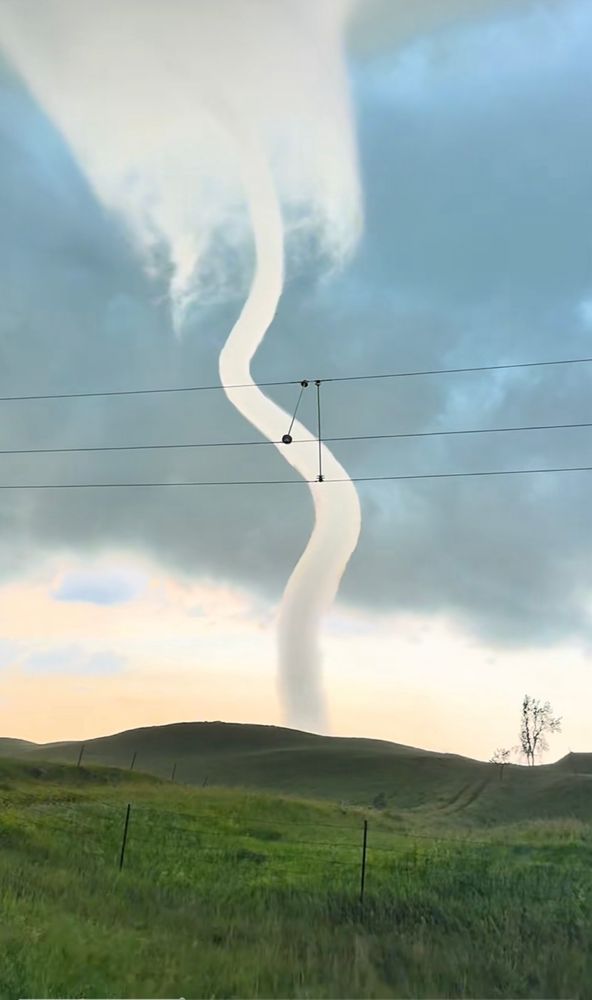 a tornado, likely a rope-like or dissipating tornado, extending from the cloud base to the ground
