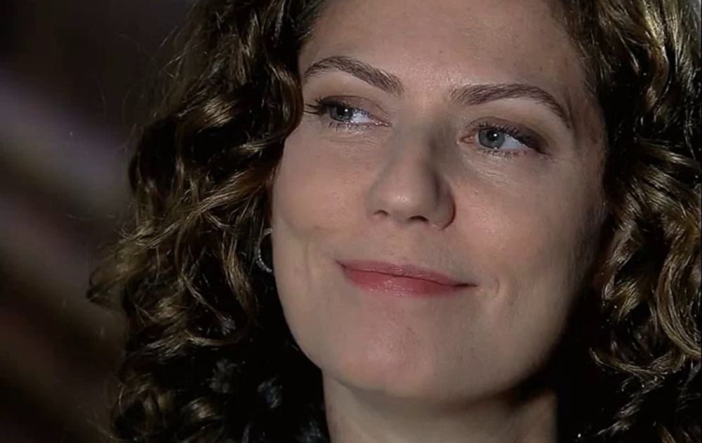 a woman with curly hair is smiling and looking up