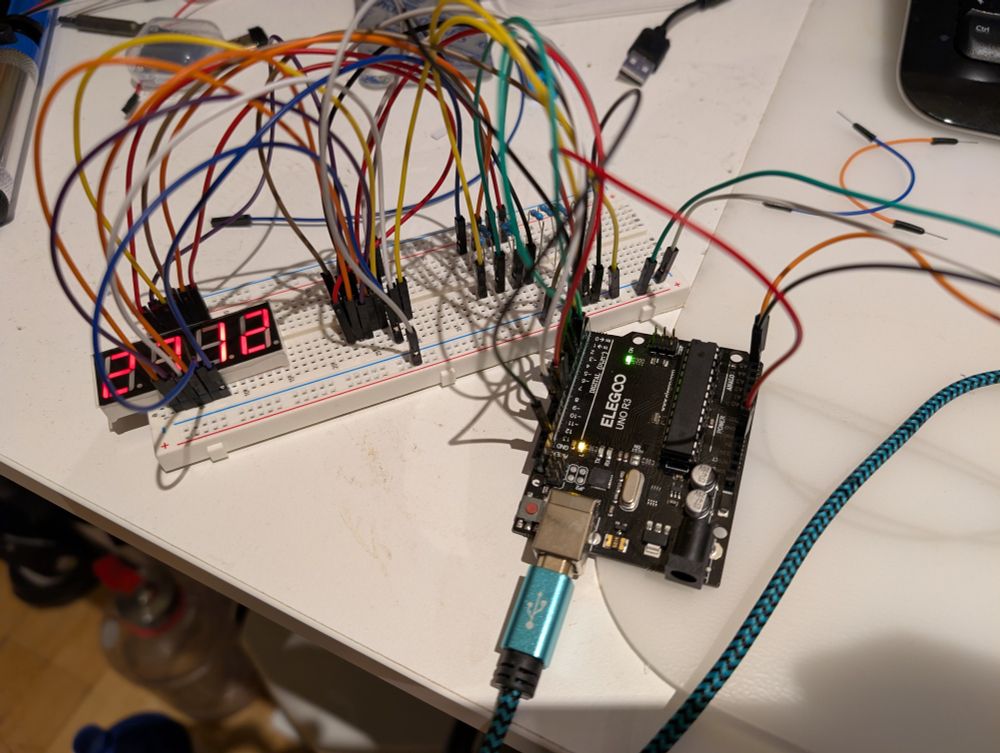 A mess of wires connected to a breadboard. 
An Arduino Uno and a 4-digit 7-segment display are barely visible. 
