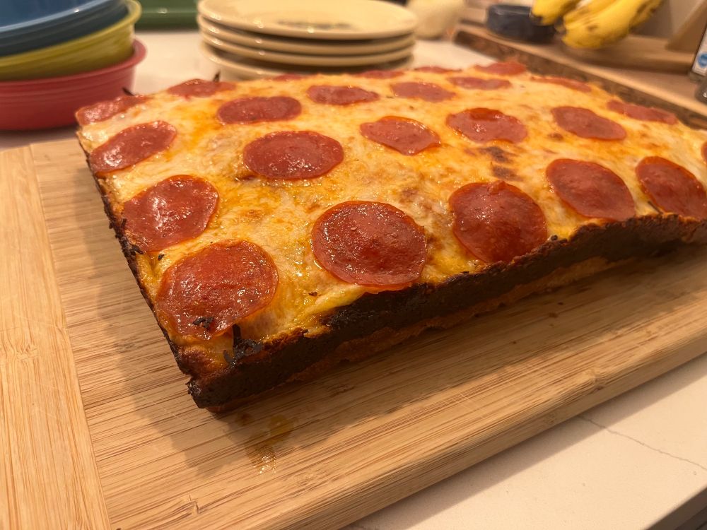 A Detroit style deep dish pizza. A rectangular pizza with crispy cheese edges and pepperoni topping.