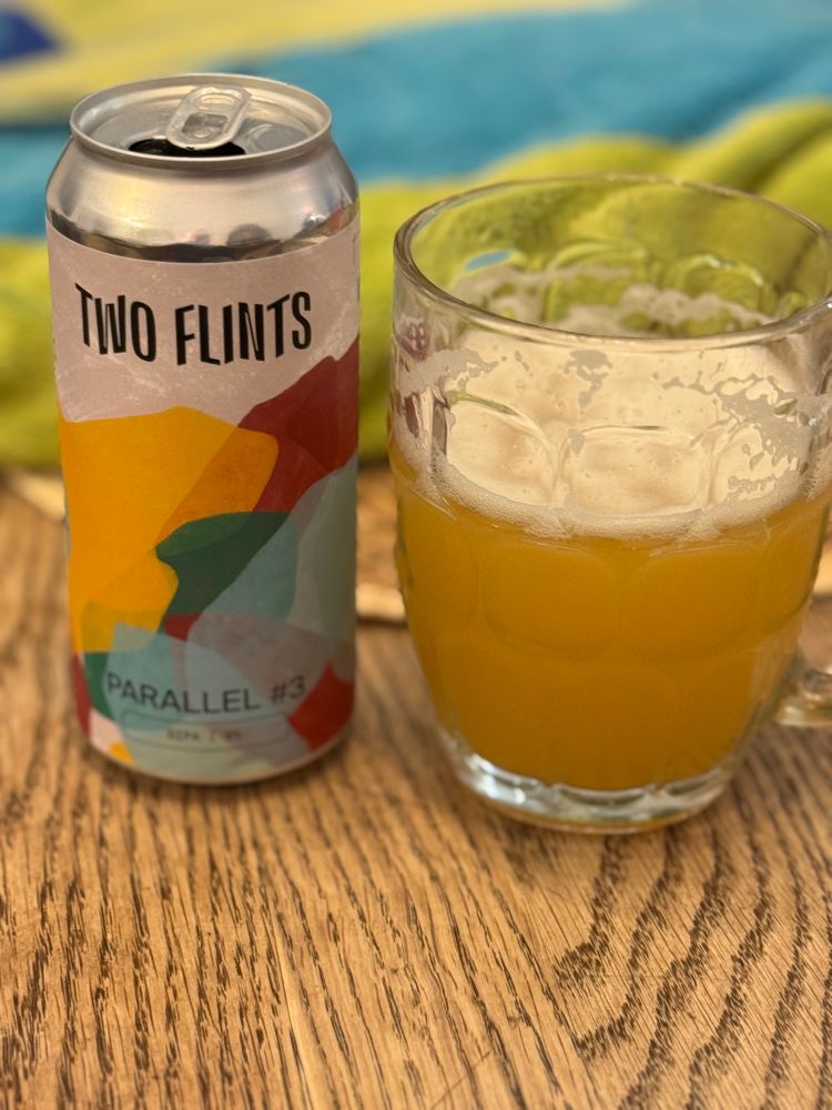A glass of Two Flints Parallel #3 DIPA next to its can.