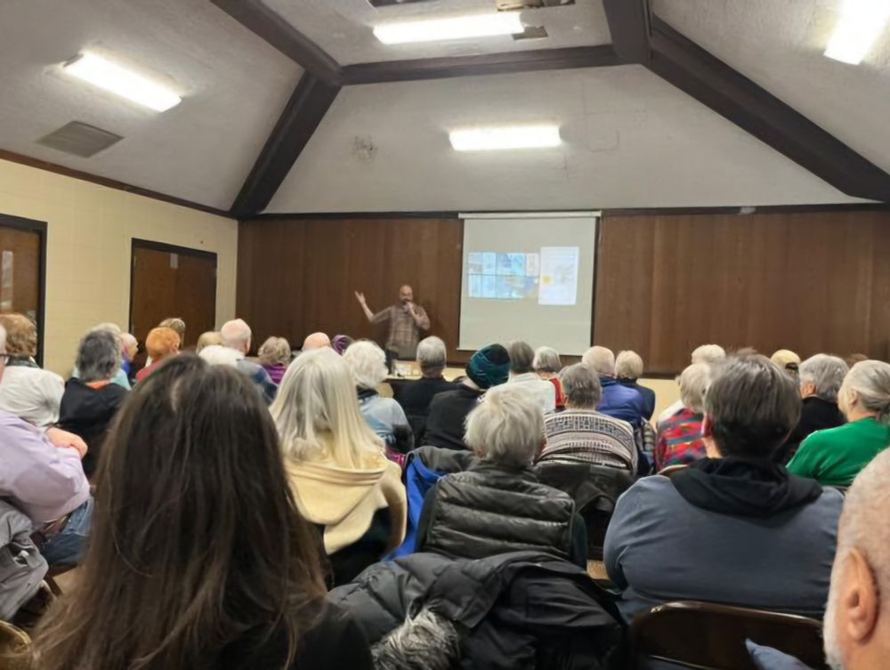 A bald man speaking to a group. Photo by Kat Beaulieu