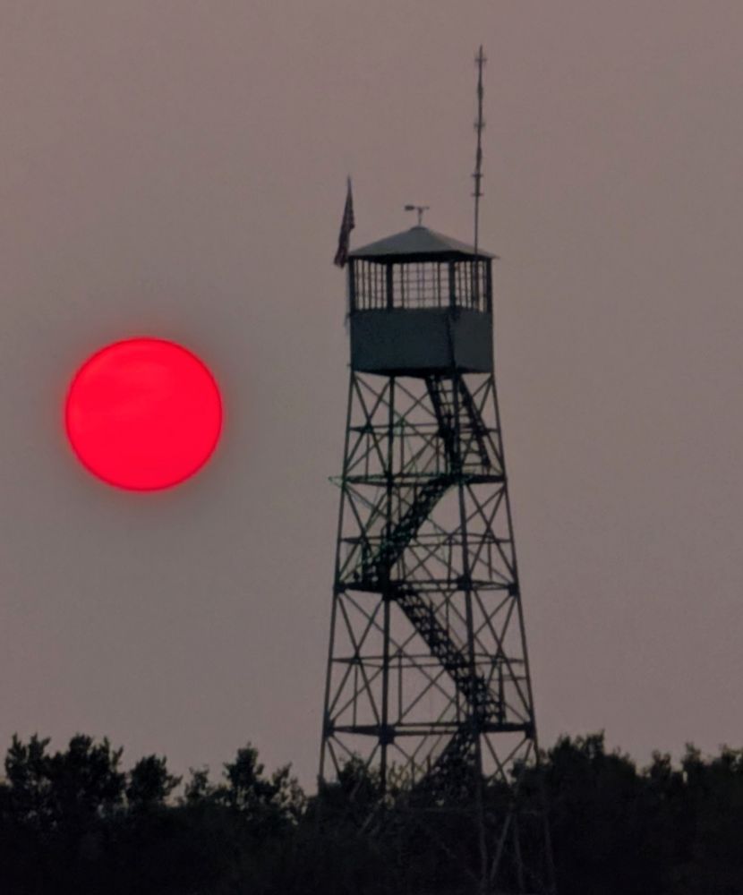 Pink wildfire sun next to a fire Tower.
