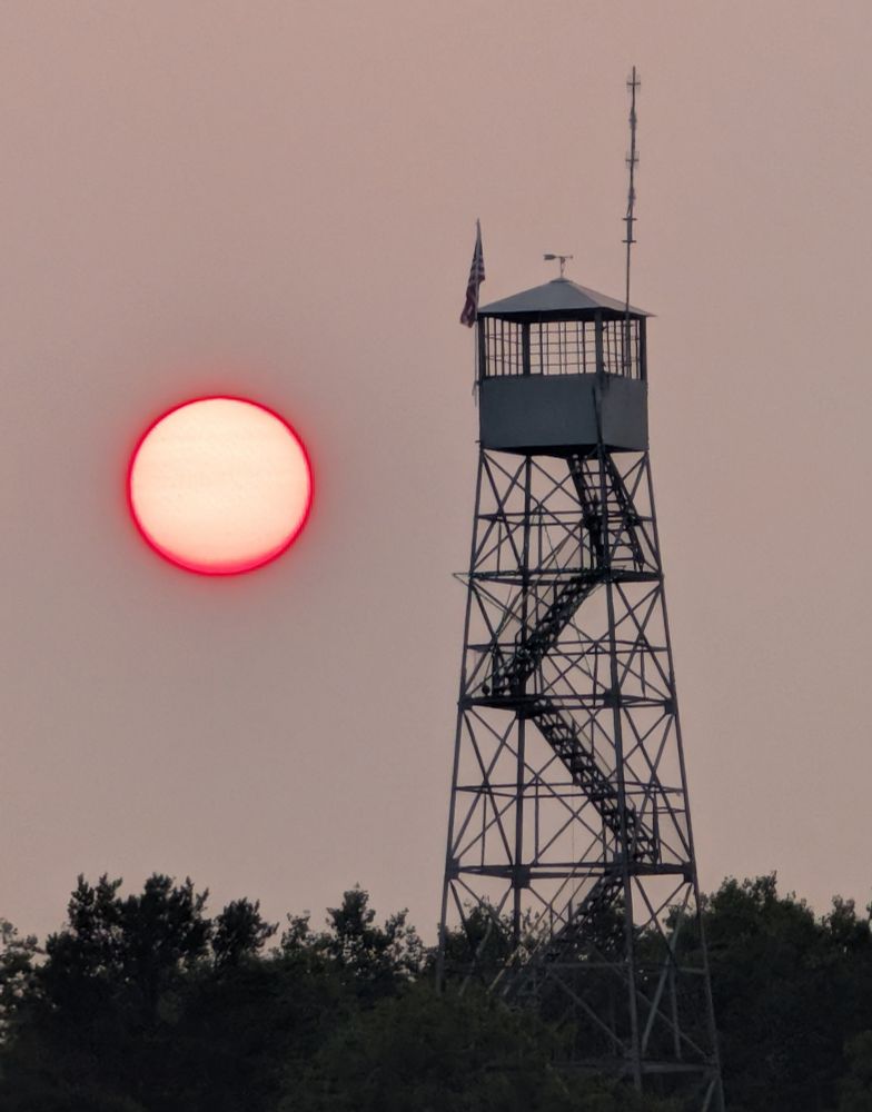 Pink wildfire Sun. Next to a fire tower