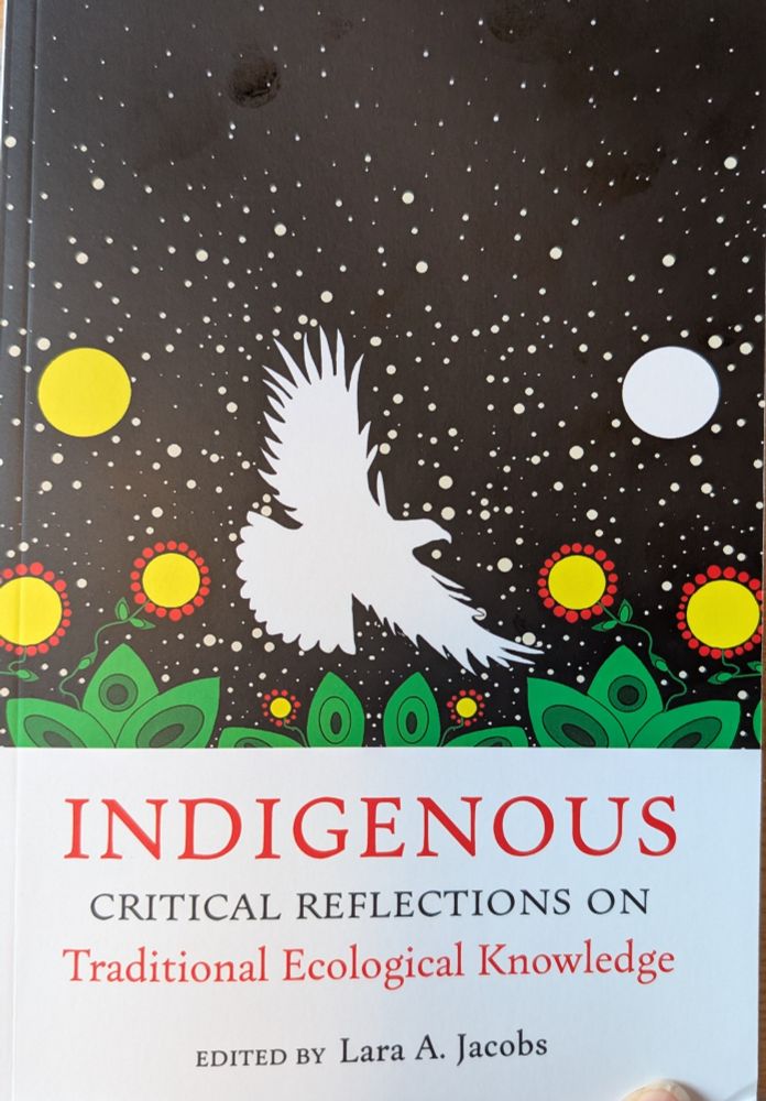 Cover for the book Indigenous: Critical reflections on traditional ecological knowledge, edited by Lara A. Jacobs. Art: black background with white stars, two circles, one is yellow and the other white, that may represent the sun and moon. Yellow center flowers with red petals rise above green leaves. 