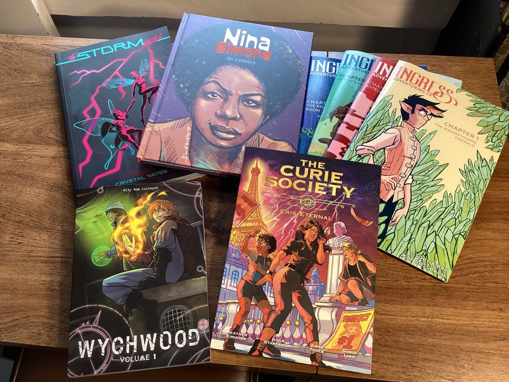 Pic of books I bought at TCAF today. The Storm Stained, by Crystal Yates; The Curie Society, by Einhorn, Staffroni, Toole, and Liao; Wychwood, by Ally Rom Colthoff; Ingress Adveturing Co, by Kay Rossbach; and Nina Simone in Comics, from NBM Graphic Novels.