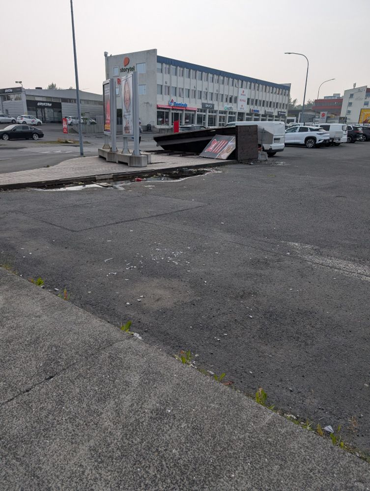 Bílaplan með glerbrotum, rusl og hús. Mmmm Skeifan