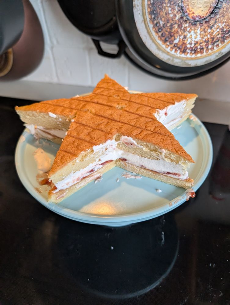 Tveggja hæða vanillu kaka í formi stjörnu með rauðri (jarðaberja) sultu og rjóma á milli.