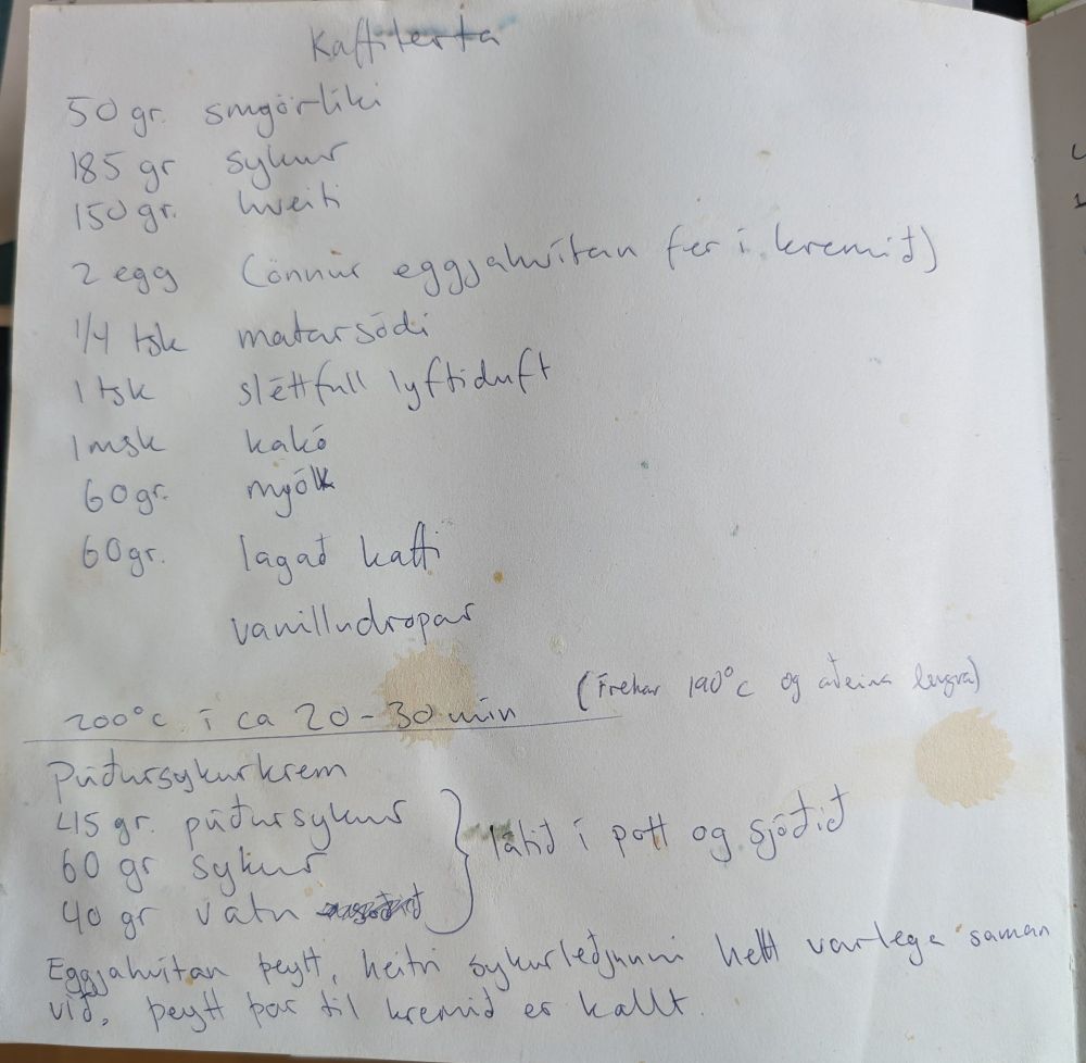 Handskrifuð uppskrift að kaffiterta og púðursykurkremi í bók með fullt af blettum á blaðsíðunni