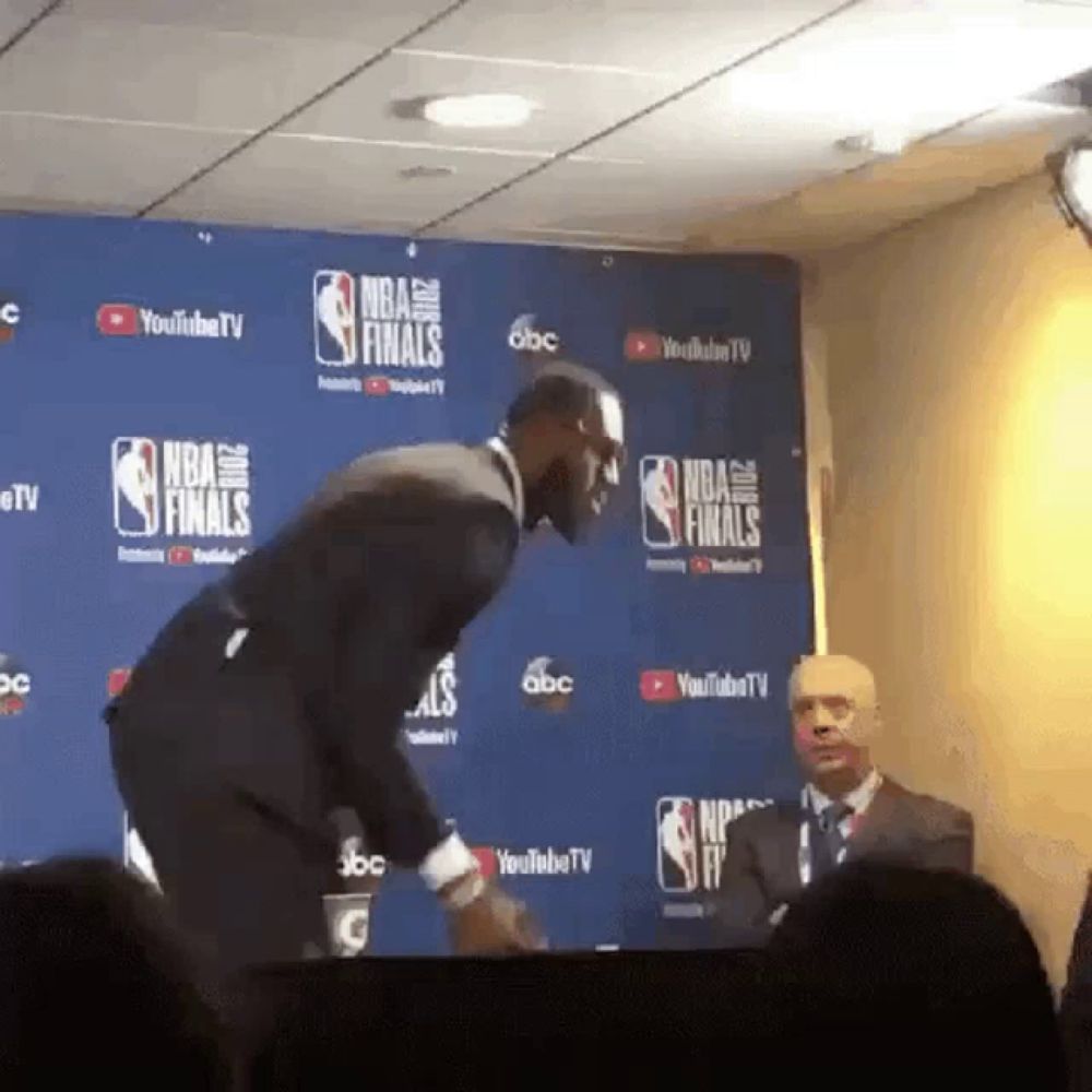 a man in a suit stands in front of a wall that says nba finals on it