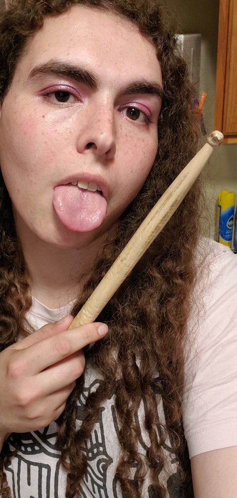Natalie with pink glittery eyeshadow holding a drumstick that has literally been charred by fire and sticking her tongue out