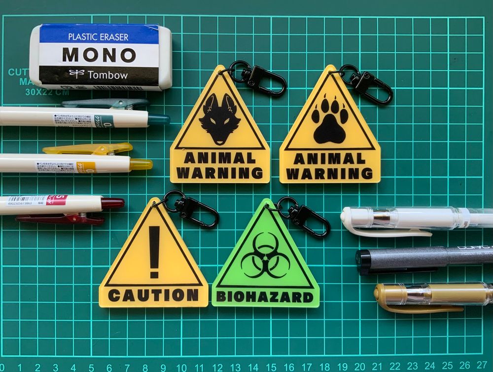 A collection of four acrylic charms stylized as safety hazard signs