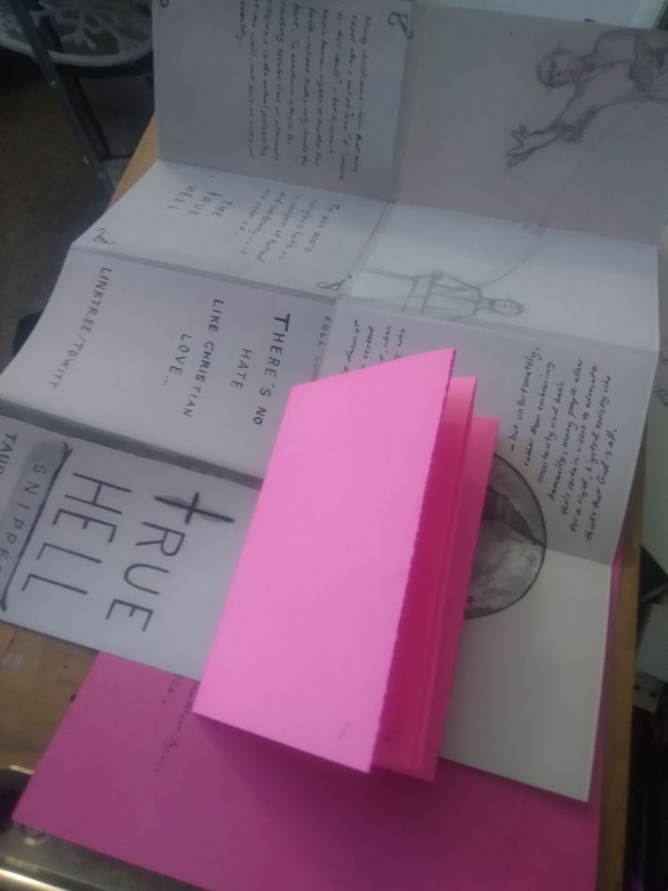 Sheets of paper and a blank zine booklet on a tablet board.