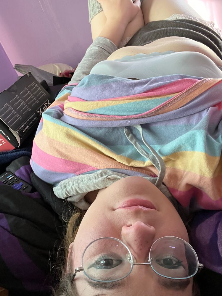 On my back, head tilted upside down, looking at the camera with a hand on my smooth little socked-thighs 💕