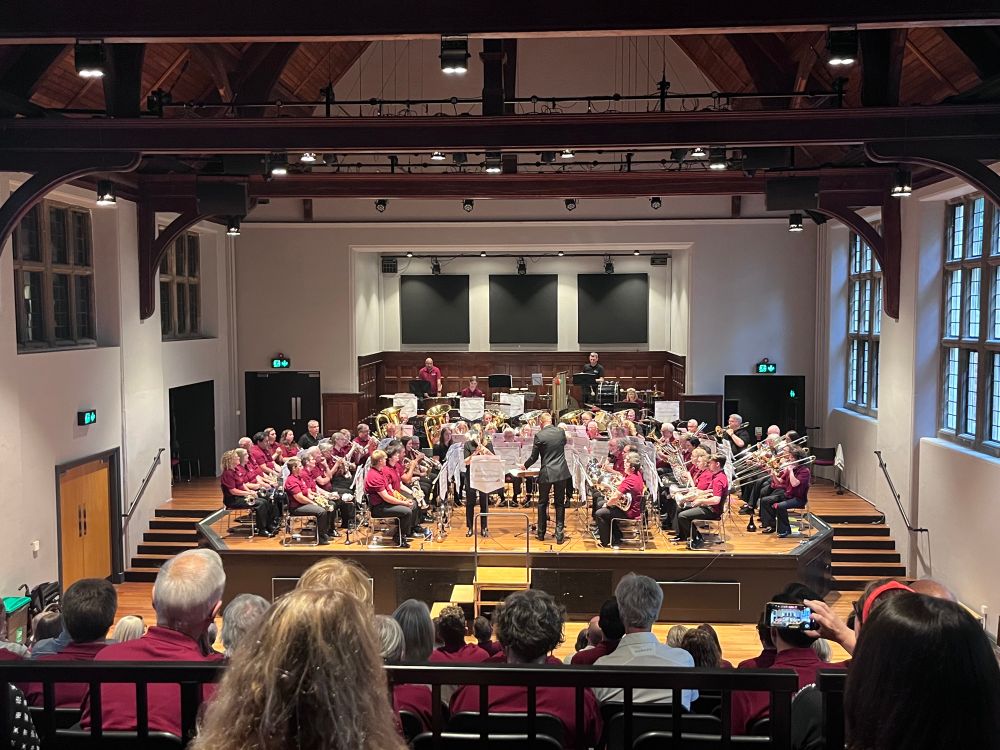 View from the audience at the final concert. There are approximately 60 in the band wearing matching burgundy tops, and at the front is one of the tutors playing a solo