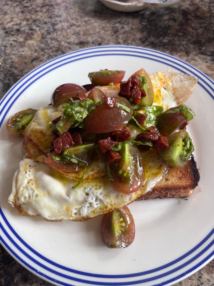 Sourdough toast, fried egg, chorizo, homegrown purple cherry tomatoes marinated in olive oil and basil
