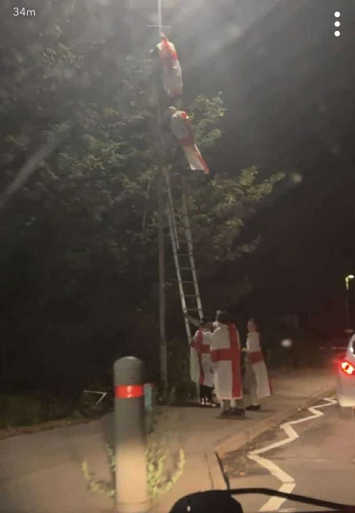 Some twats with flags wrapped round them putting flags on lampposts. They have a ladder 