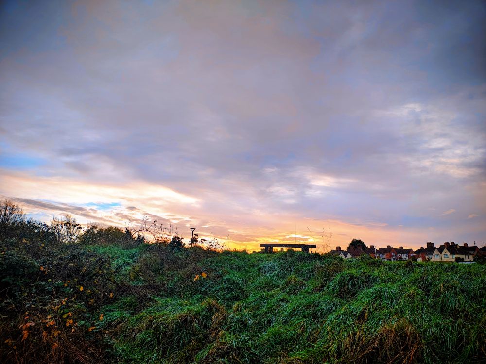 A bench on a hill illuminated by the sun rising behind 