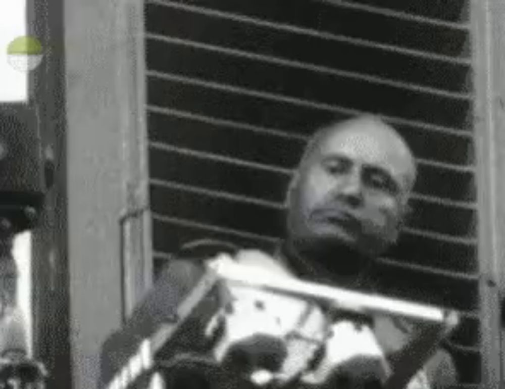 a black and white photo of a man laying in a chair with a gun .