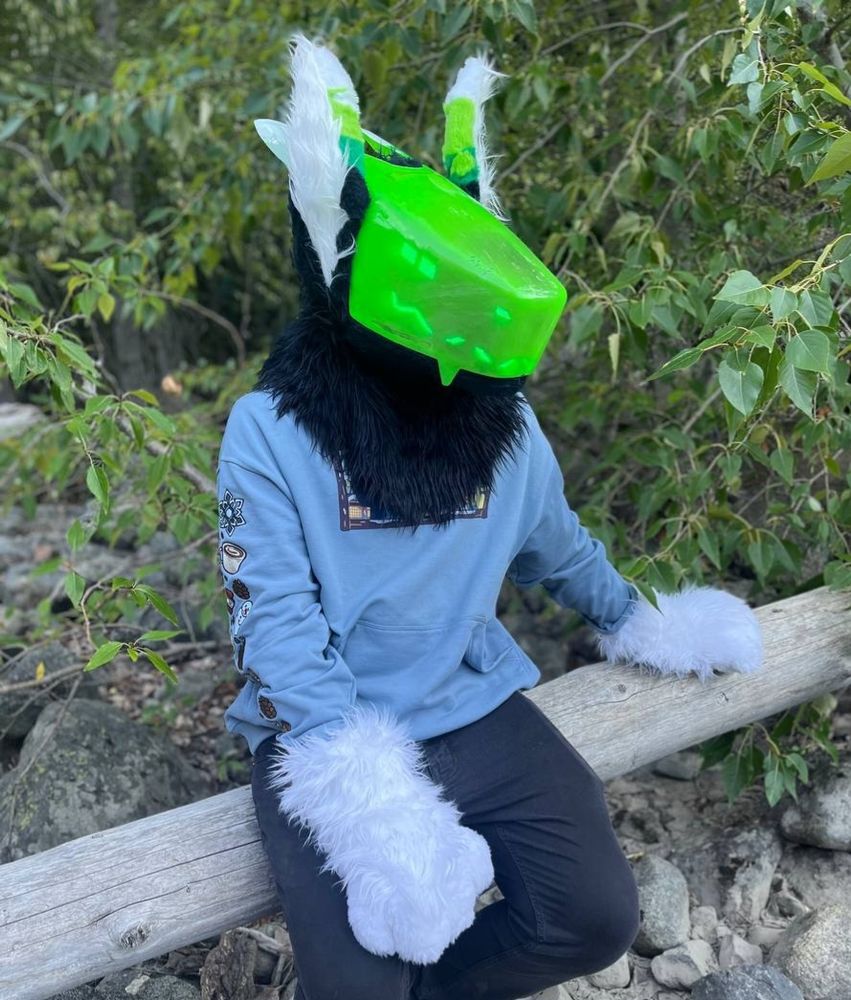 Gamebeast partial fursuiter sitting on a fallen tree.