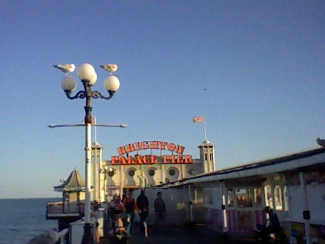 Brighton Palace Pier arcade entrance, two seagulls are stood on top of a lampost in the foreground