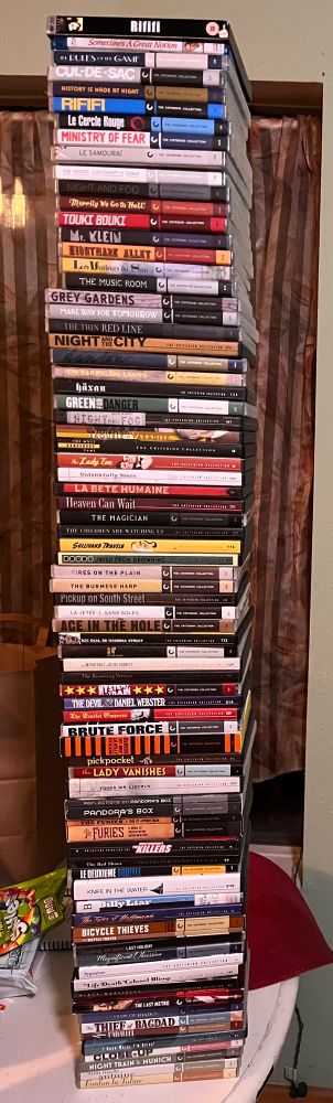 80 Criterion DVDs and Blus, stacked on a table. 