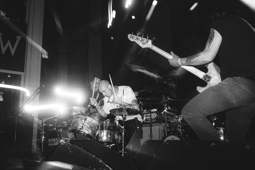 The band, HELP - performing on stage at a recent show. Light trails from a slow shutter shine on the upper borders of the image. Pic in monochrome