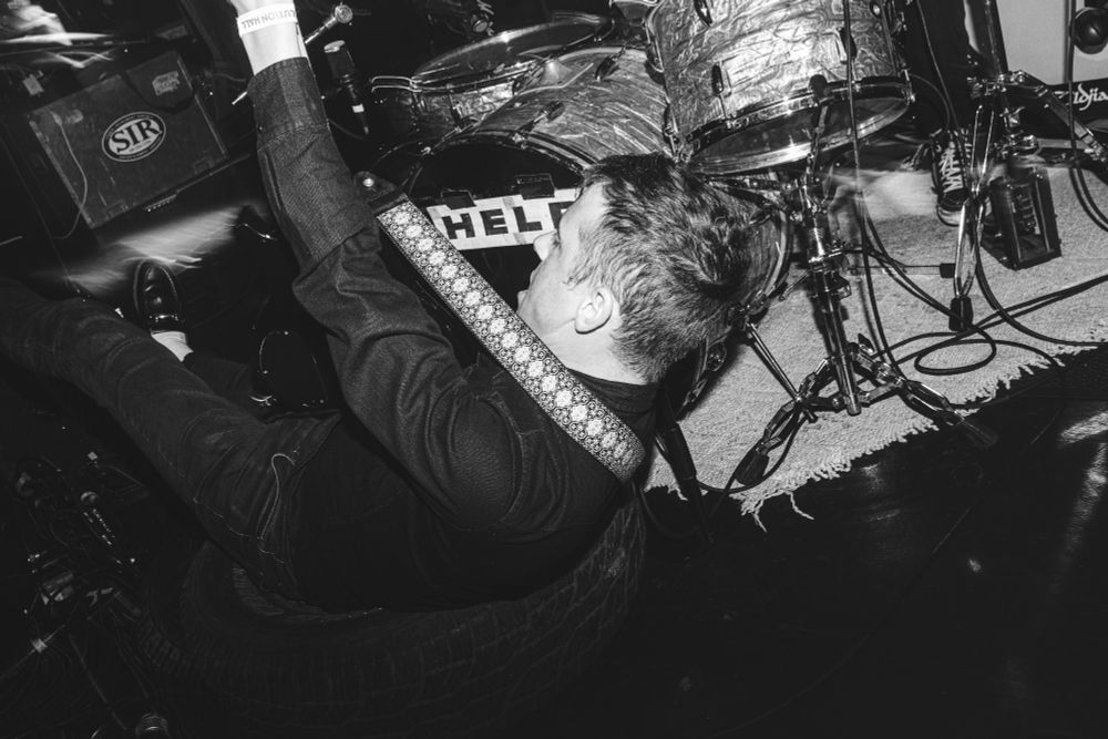 The guitarist for the band, HELP, falling onto a tire in front of their drum set during a recent concert 