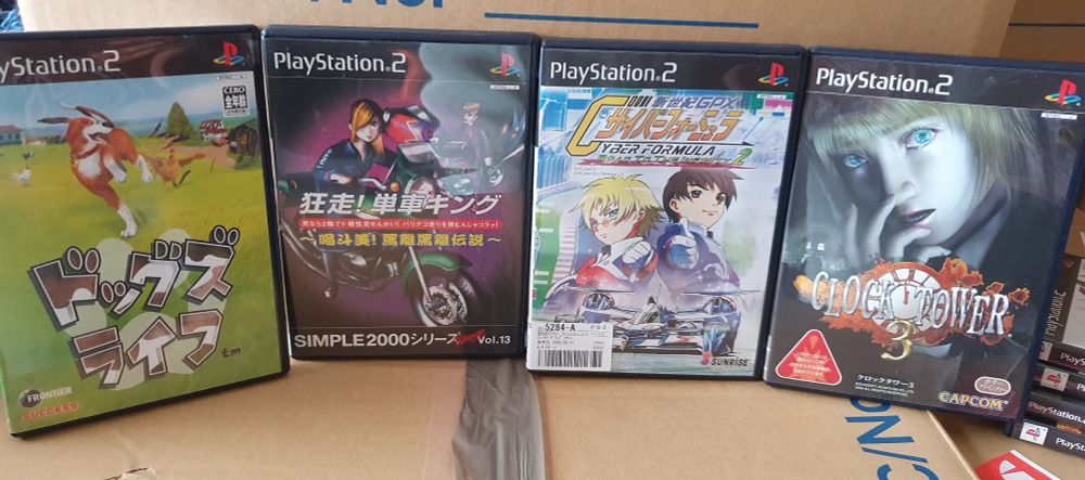 4 Japanese PS2 games propped face up on some cardboard boxes. From left to right: Dog's Life, Motorbike King, GXP Road to Infinity 2 and Clock Tower 3