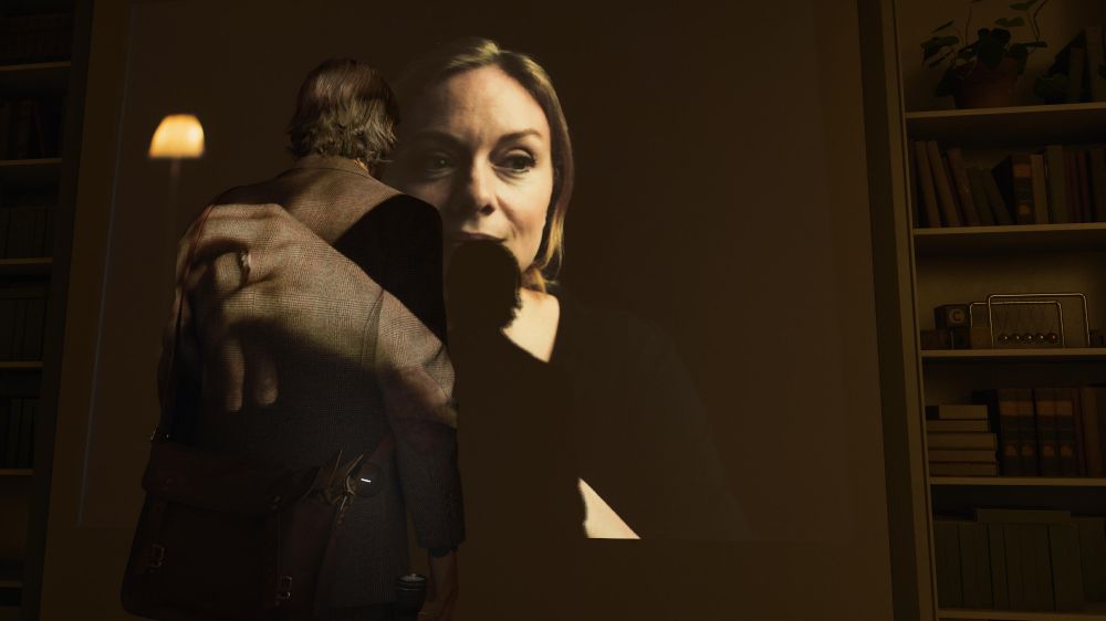 Alan Wake standing in front of a projection of a live action woman