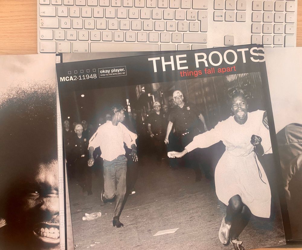 Pochette du triple vinyle du groupe The Roots posée sur le bureau… 

comme par hasard il va prendre l’air en passant devant un disquaire et comme par hasard il tombe sur ce coffret…  