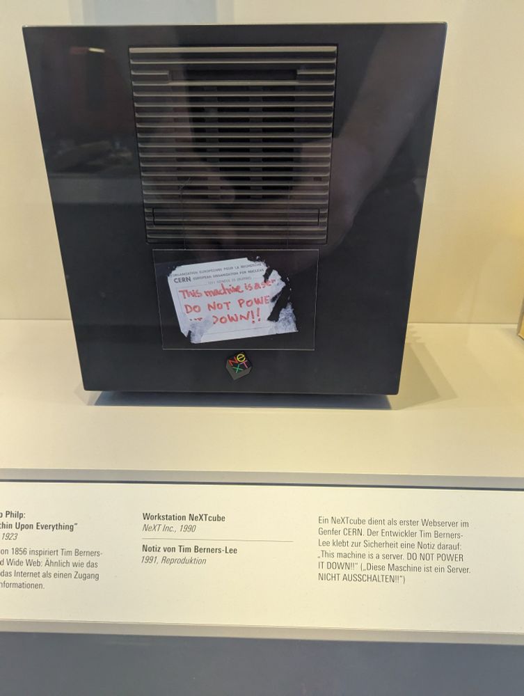 An Apple Next Cube on display in a museum. The exhibit label translates to: 

NeXTcube Workstation, NeXT Inc., 1990

Note by Tim Berners-Lee, 1991, reproduction

A NeXTcube serves as the first web server at CERN in Geneva. Developer Tim Berners-Lee sticks a note on it for safety: "This machine is a server. DO NOT POWER IT DOWN!!"