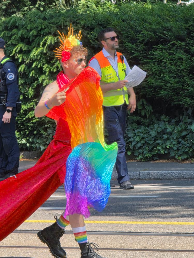 Junger Mann in Regenbogen Kleid mit lange Schleppe 