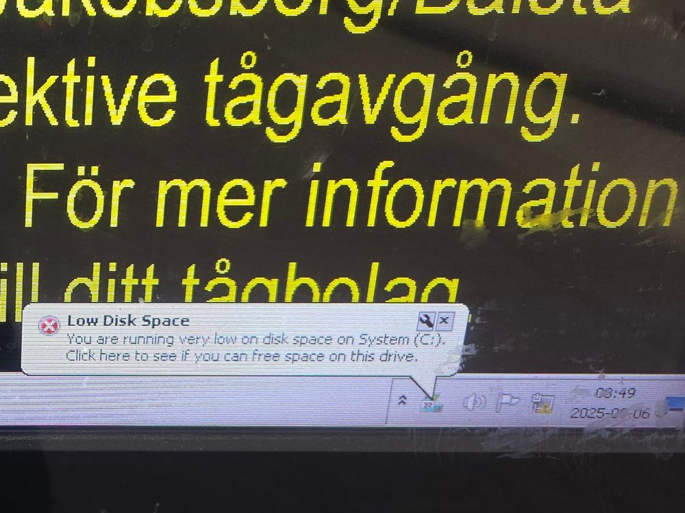 Photo of train information display showing a Windows system message saying "Low Disk Space"