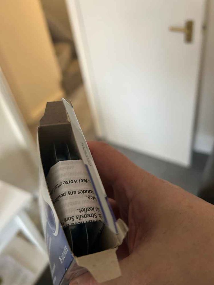 An opened box of Strepsils at the end with the info leaflet wrapped around the lozenges. 