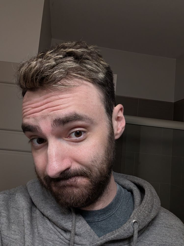 Me in a gray hoodie showing off my new haircut and highlights. Buzzed on the sides with a little longer on top. Light highlights on top contrasting my dark brown hair