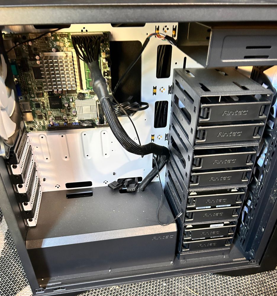 A computer case with a MicroItx mother board and a stack of 8 3.5 hard drives on the right. 